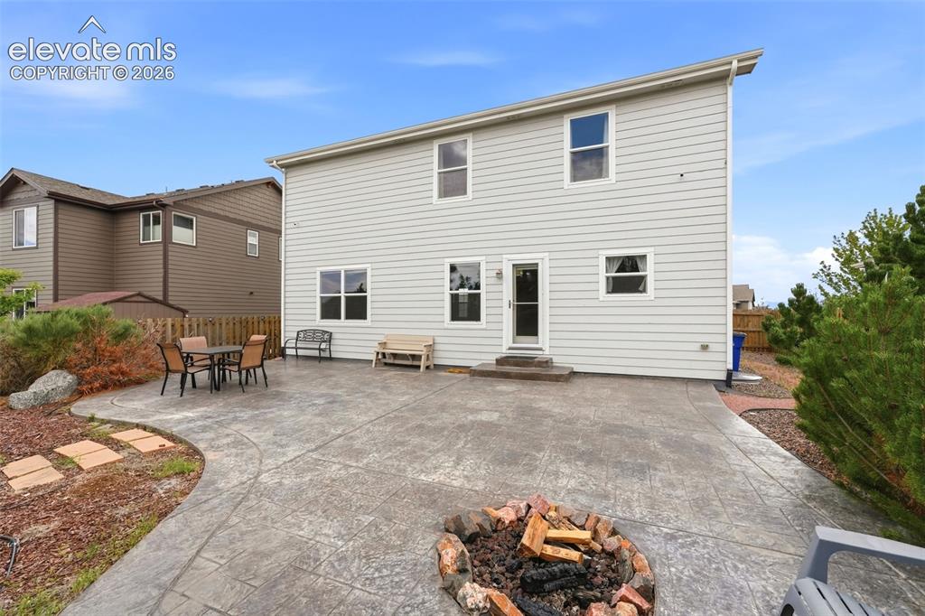 Image 29 of 33: Expansive stamped concrete patio with built-in fire pit, multiple windows, 