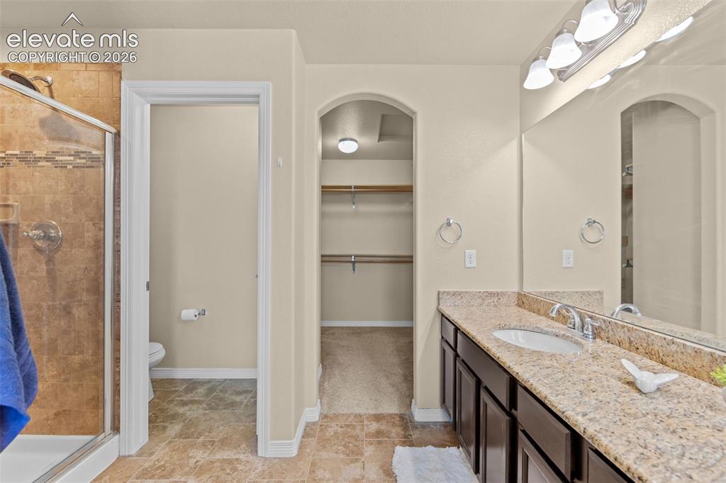 Image 24 of 44: primary bath with dual vanity and linen closet, separate toilet water close