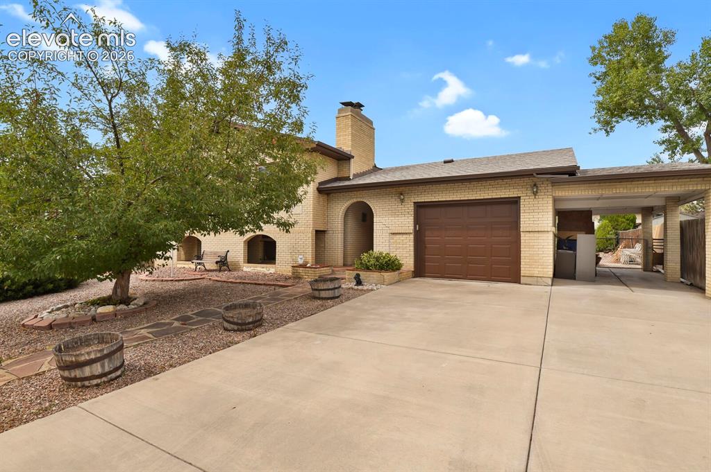Image 1 of 48: Brick exterior with arched window details, attached garage, and a covered c