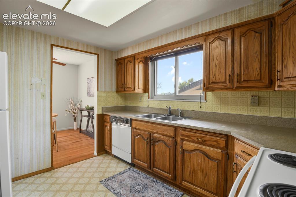 Image 17 of 48: Kitchen featuring wood cabinetry, laminate countertops, a double basin sink