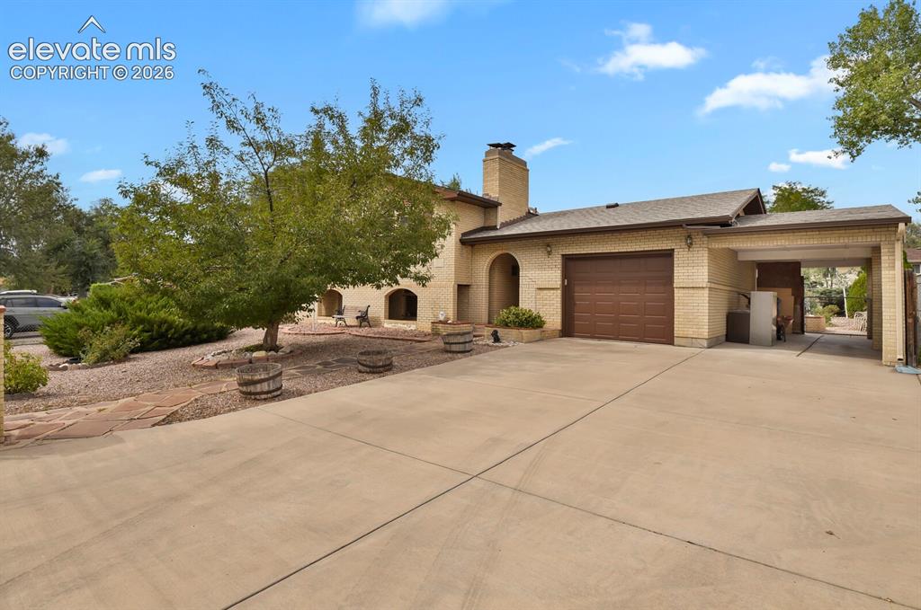 Image 4 of 48: Brick exterior with arched entryways, integrated garage, attached carport,
