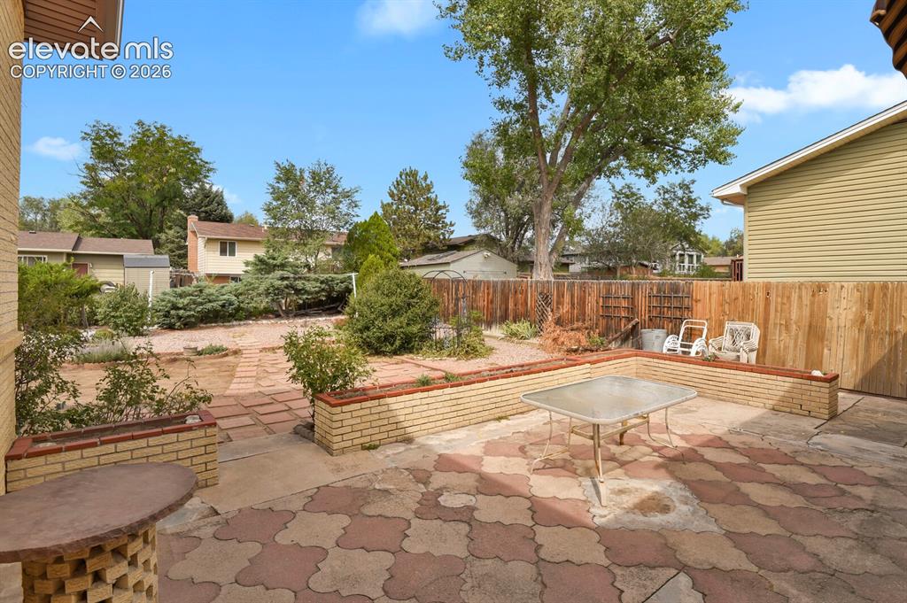 Image 40 of 48: Expansive outdoor patio with patterned pavers, brick-faced retaining walls,