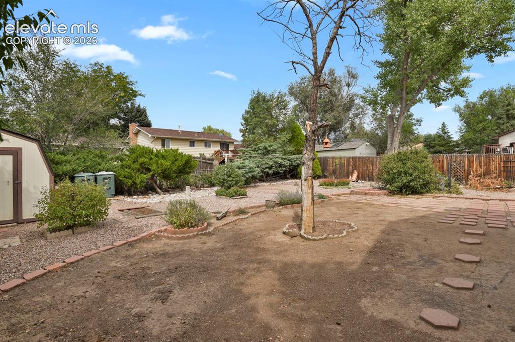 Image 43 of 48: Expansive backyard featuring a storage shed, established trees, and decorat