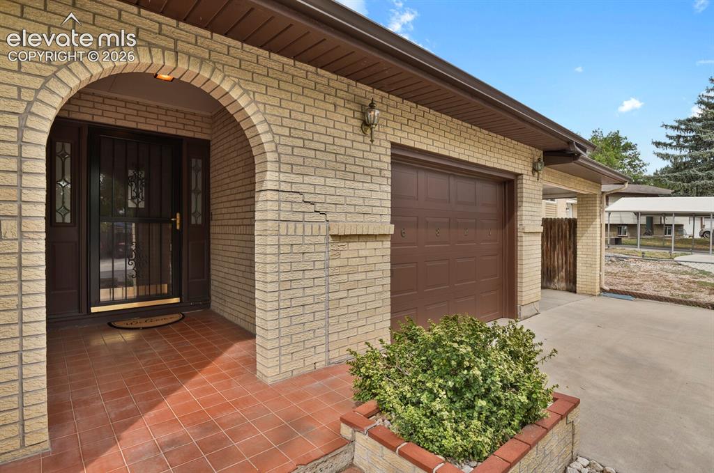 Image 5 of 48: Brick exterior with an arched entry, attached garage, and a tiled entryway