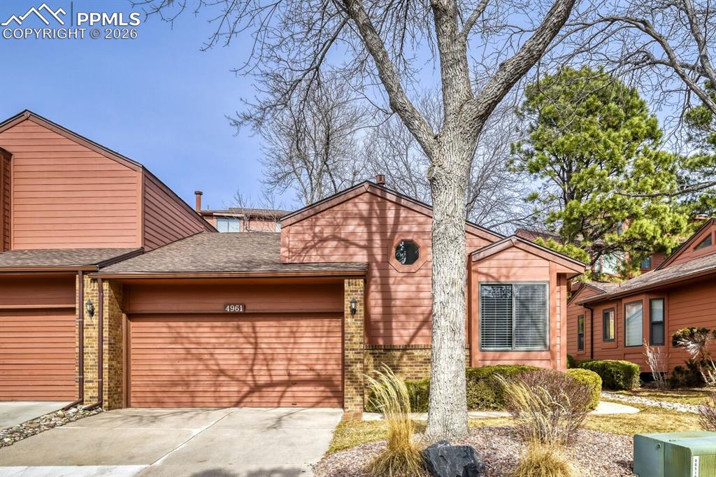 Image 1 of 34: View of front facade with brick siding, a garage, roof with shingles, and d
