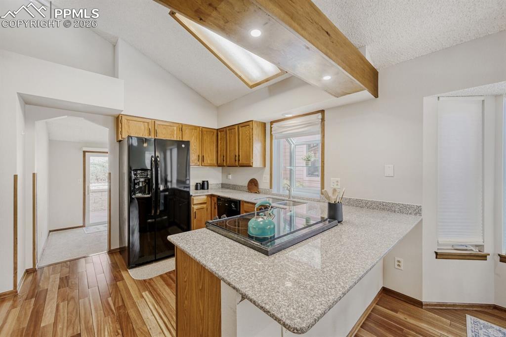 Image 10 of 34: Kitchen featuring light wood-style flooring, black appliances, wood finish 