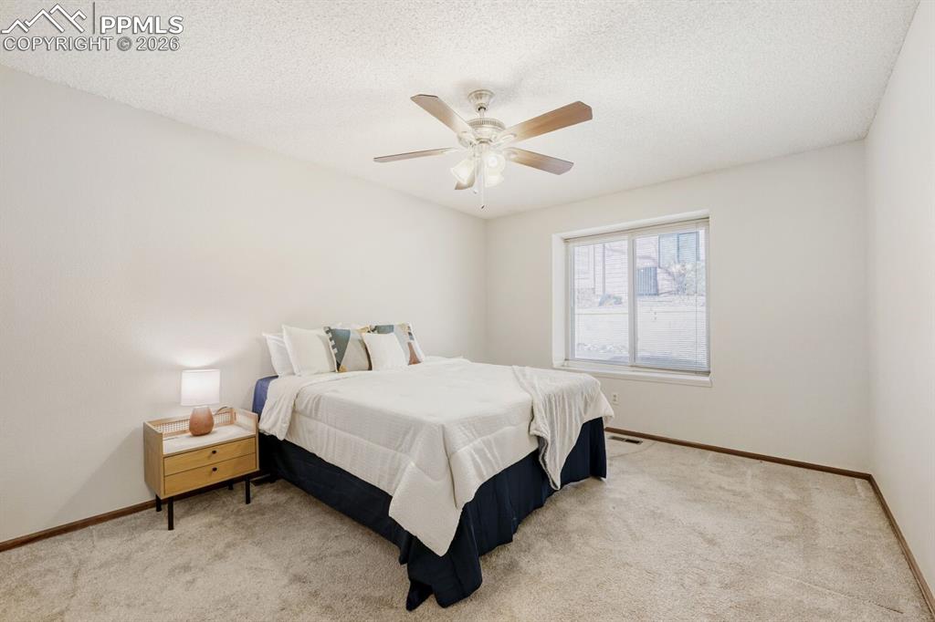 Image 17 of 34: Bedroom with light colored carpet, a ceiling fan, and a textured ceiling