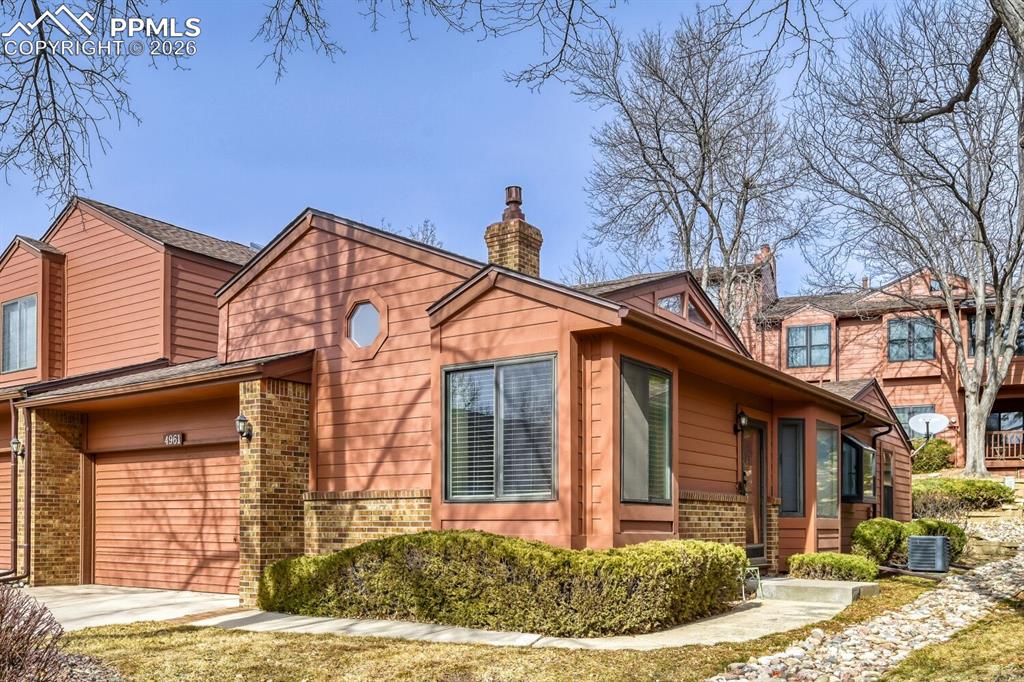 Image 2 of 34: View of property exterior with brick siding, a chimney, and an attached gar