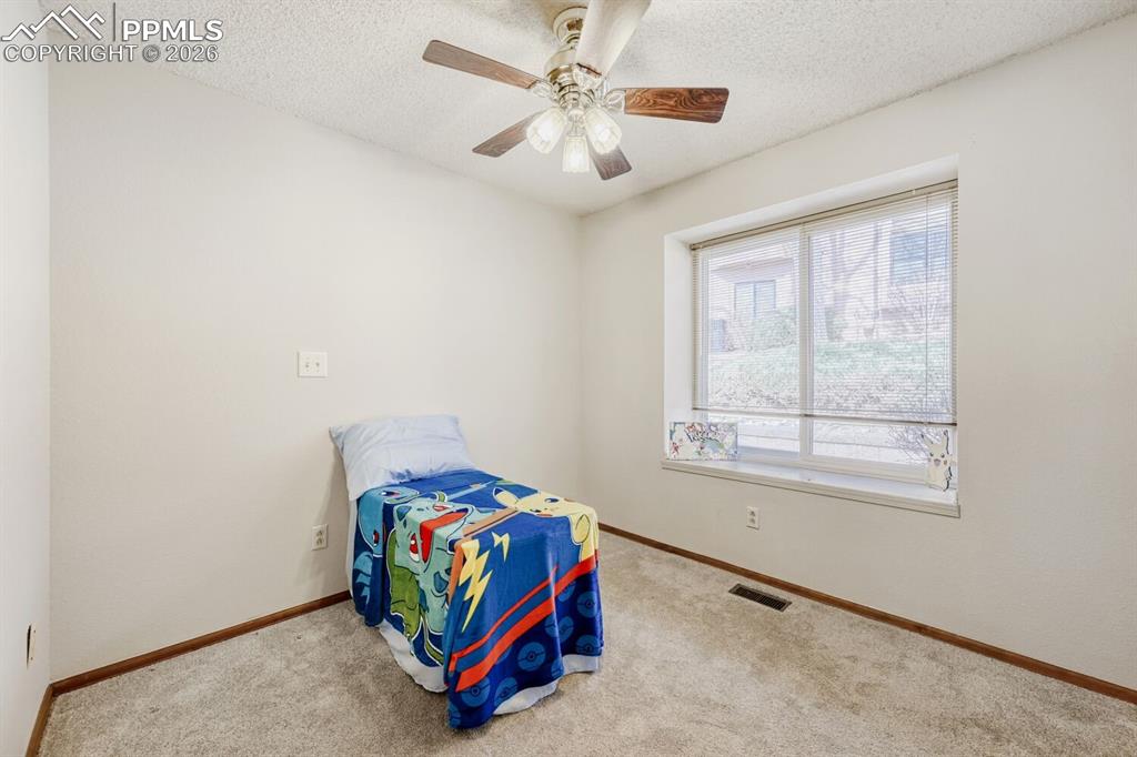 Image 22 of 34: Bedroom with a textured ceiling, ceiling fan, and carpet