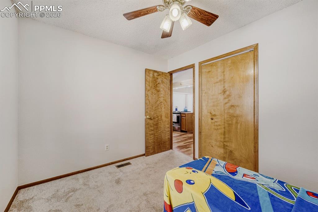Image 24 of 34: Bedroom with a textured ceiling, carpet, a ceiling fan, and a closet