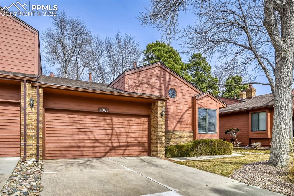 Image 3 of 34: View of front of property featuring brick siding, driveway, a garage, and r