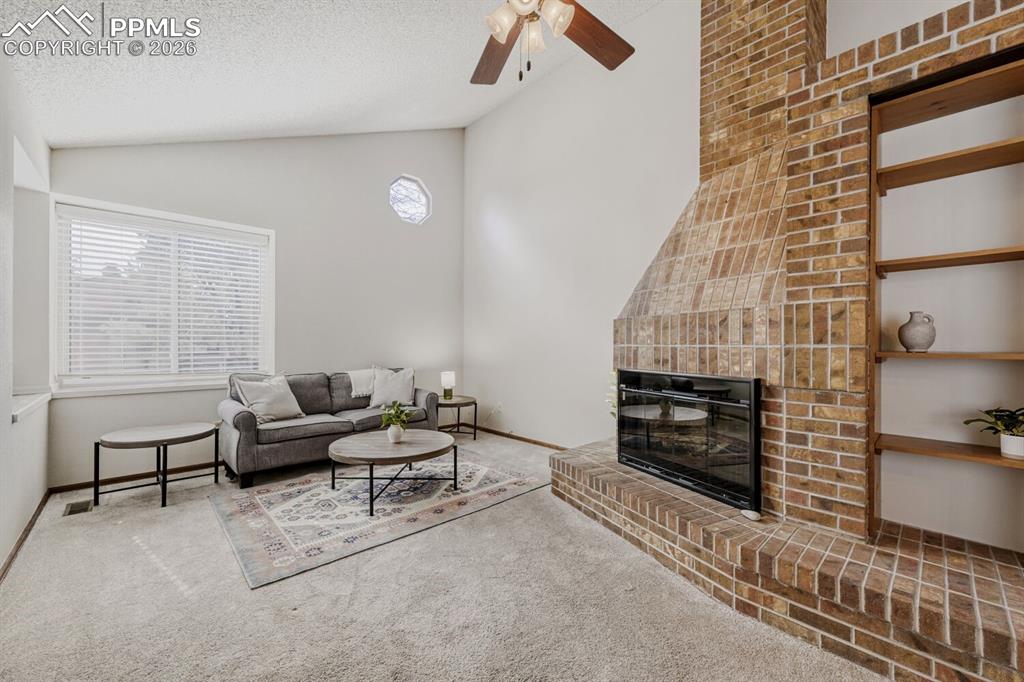 Image 4 of 34: Carpeted living room with a ceiling fan and a glass covered fireplace