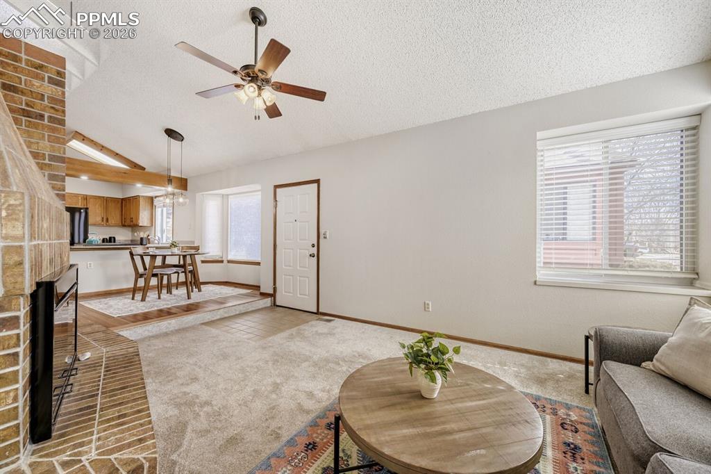 Image 6 of 34: Living area featuring carpet floors, ceiling fan, and a brick fireplace