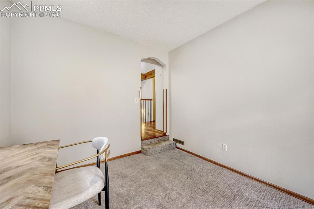 Image 9 of 34: Unfurnished office with arched walkways, carpet floors, and a textured ceil