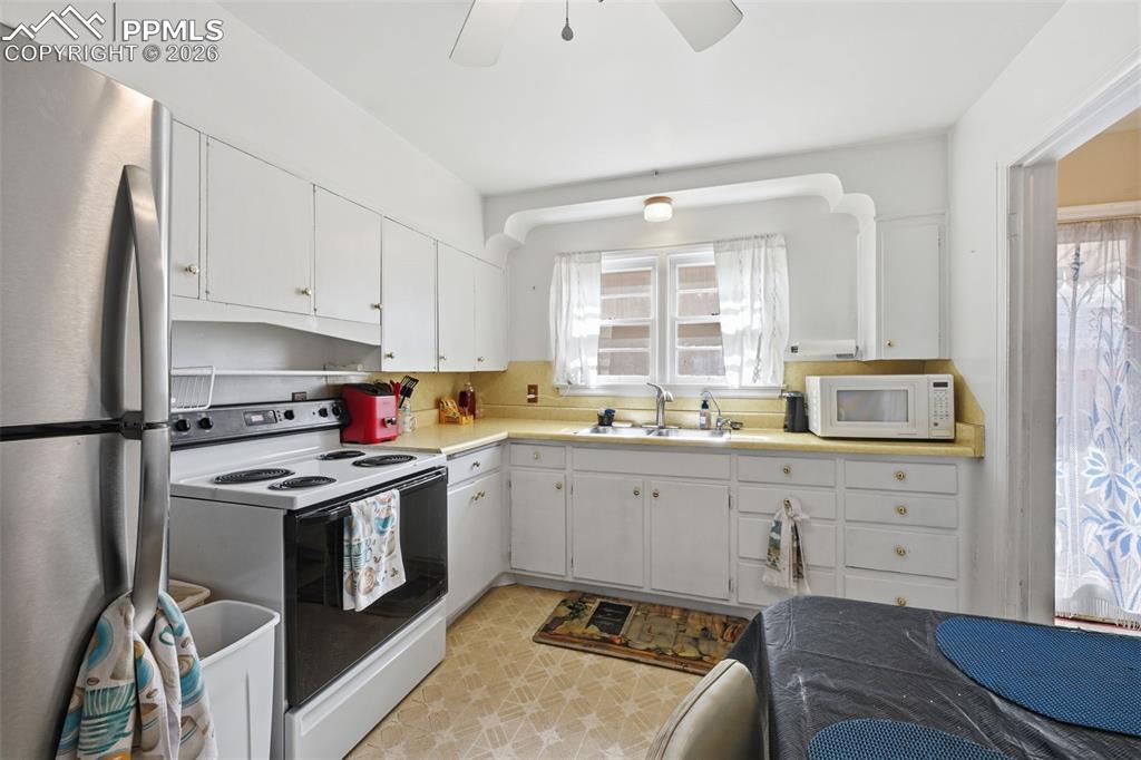 Image 10 of 23: Kitchen with white appliances, light countertops, white cabinetry, light fl