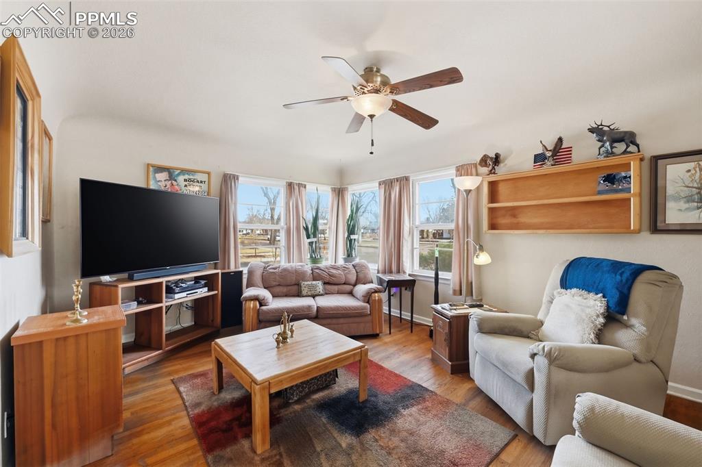 Image 9 of 23: Living area with ceiling fan and wood finished floors