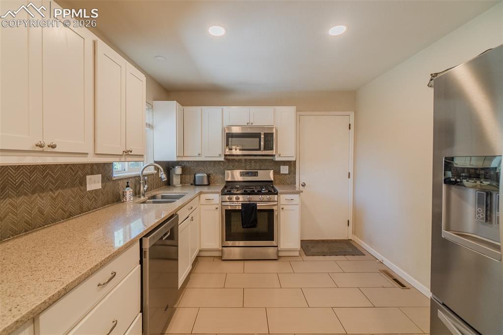 Image 10 of 31: Kitchen featuring white cabinetry, light-toned countertops, stainless steel