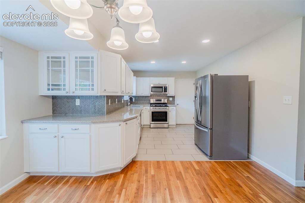 Image 10 of 42: Kitchen featuring white cabinetry, light-toned countertops, a full stainles