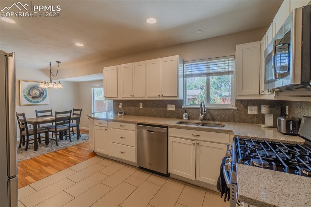 Image 11 of 31: Kitchen with window to the back yard, white shaker cabinetry, stainless ste