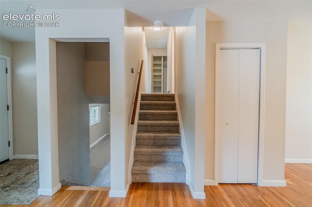Image 11 of 42: Hardwood flooring, carpeted staircase with wood handrail, white trim, and b