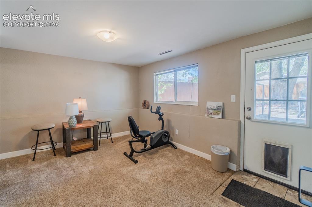 Image 12 of 30: Carpeted interior space currently used as a home gym with access to the bac