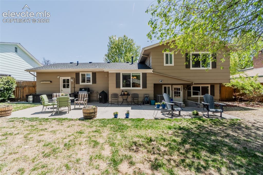 Image 13 of 30: Expansive backyard featuring a concrete patio, exterior access points, and