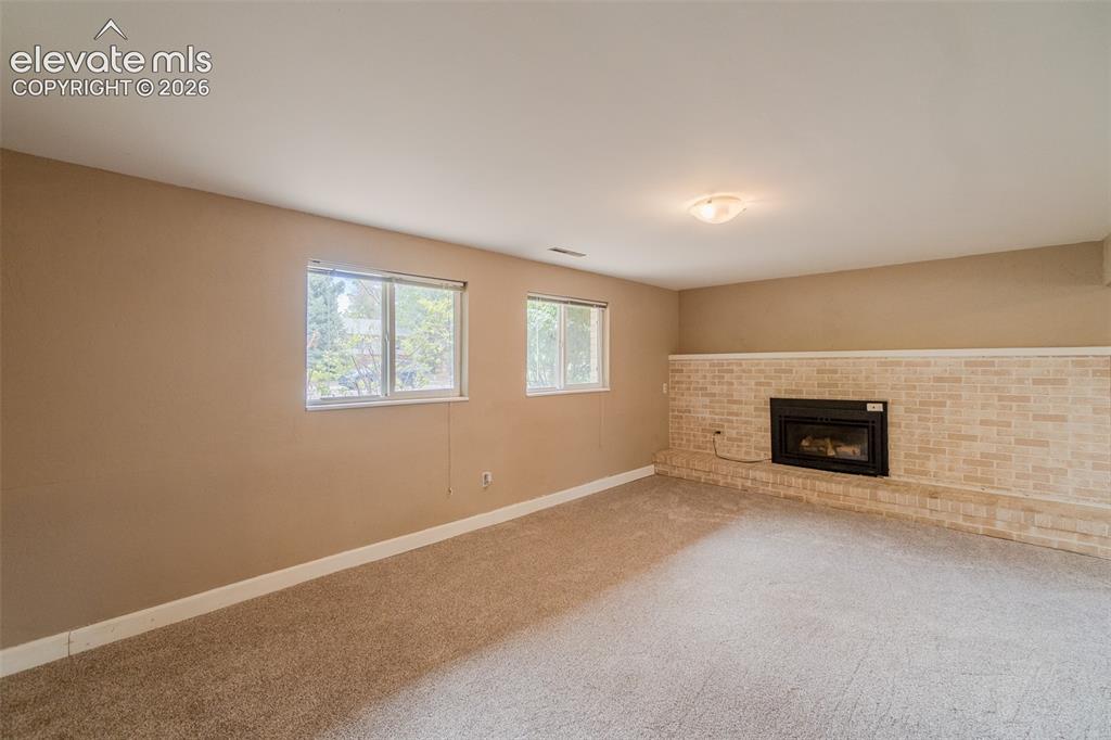 Image 13 of 42: Recessed fireplace with a light brick surround, neutral wall paint, two win