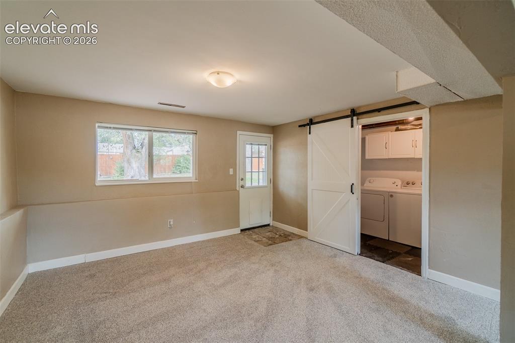 Image 14 of 42: Carpeted room with a barn door entry to a utility area featuring white cabi