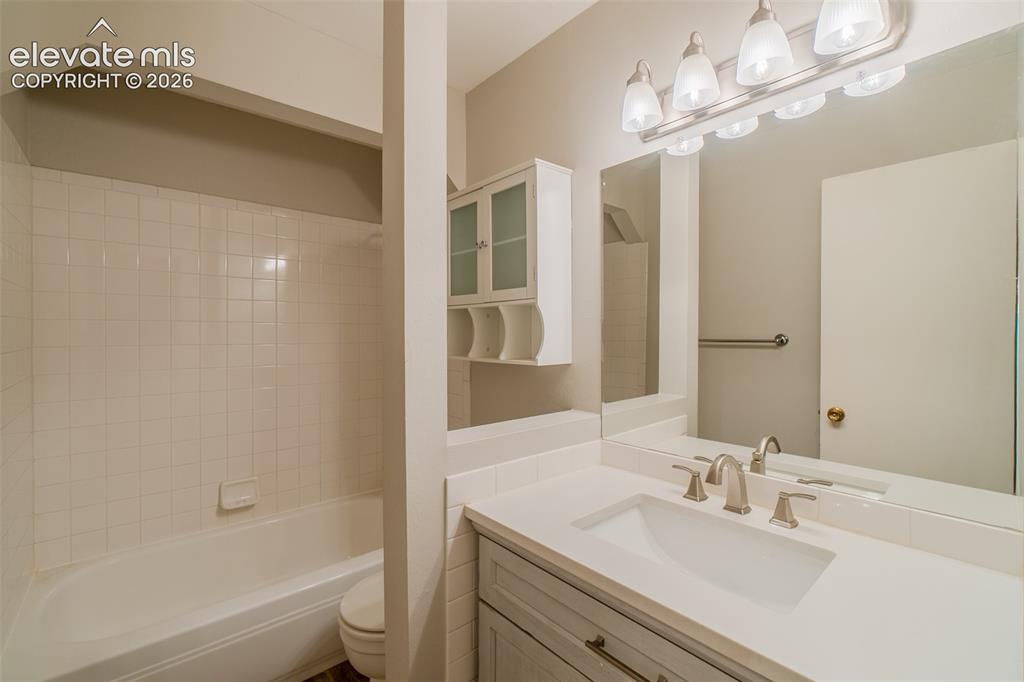 Image 21 of 42: Bathroom featuring a single vanity with an integrated sink, broad mirror, a