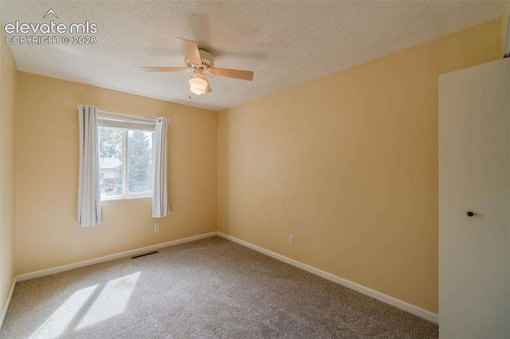 Image 22 of 42: Carpeted room with a ceiling fan, a window with curtains, and a built-in cl