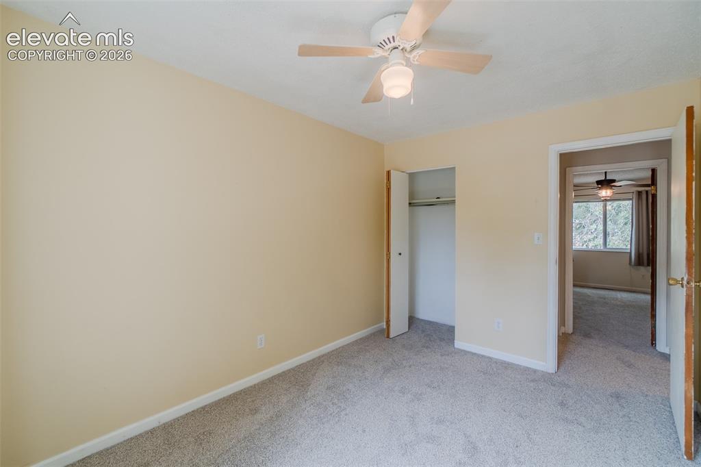 Image 23 of 42: Neutral tone wall paint, light gray carpet flooring, ceiling fan with light