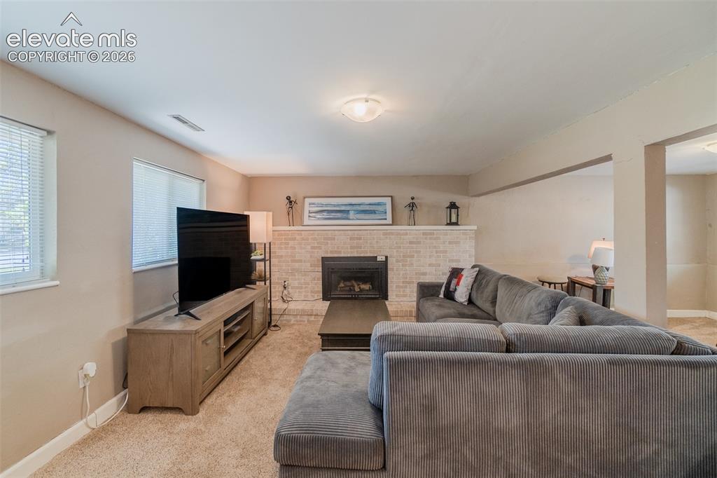Image 28 of 30: Living area featuring a light brick-finish fireplace with mantel, recessed