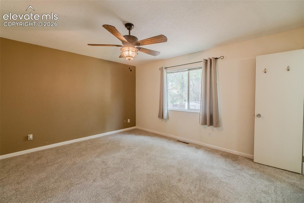 Image 29 of 42: Ceiling fan with integrated lighting, window with drapes, neutral tone carp