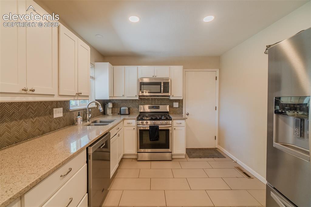 Image 3 of 30: Kitchen featuring white cabinetry, light-toned countertops, stainless steel