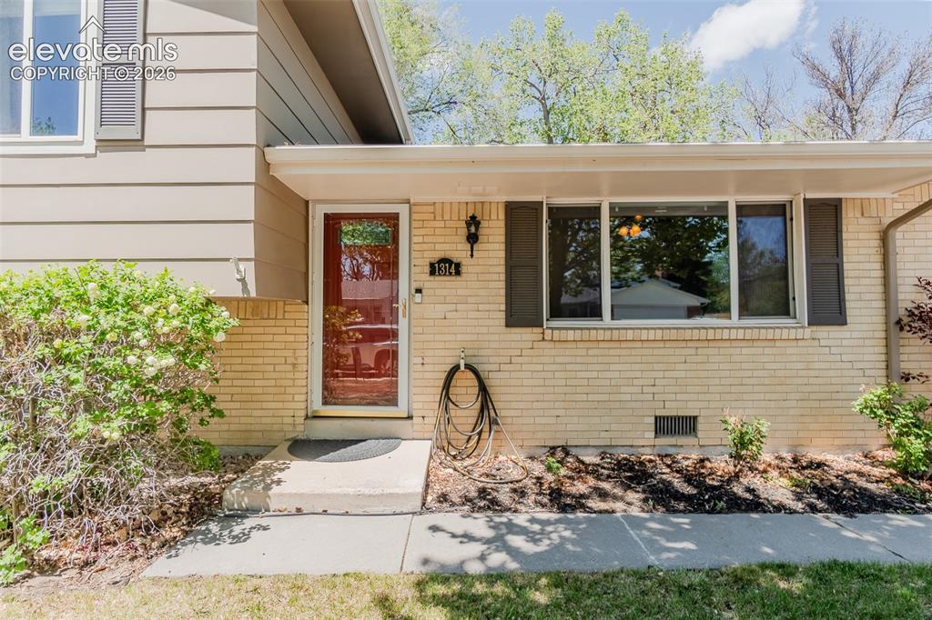 Image 30 of 30: Exterior featuring a red front door with sidelight, light brick facade, hor