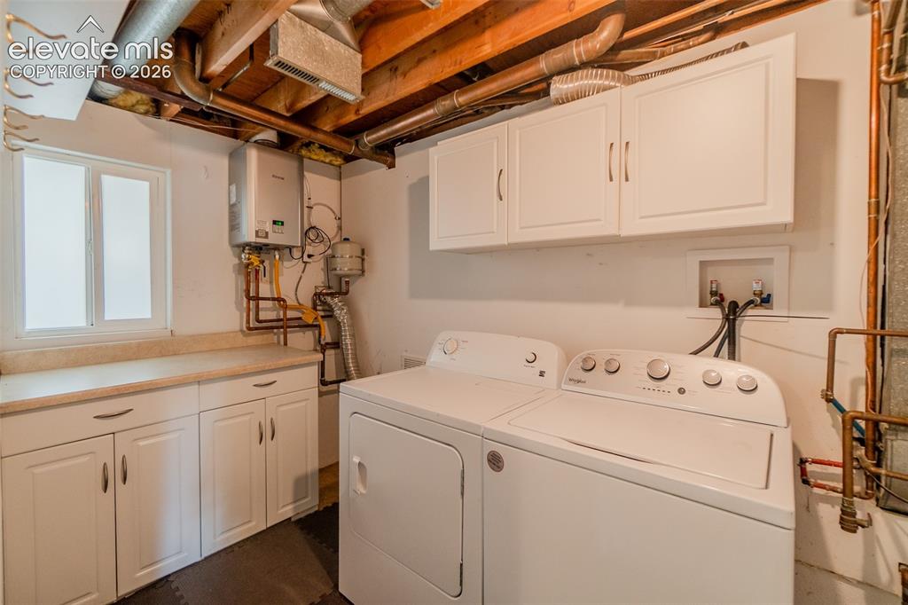 Image 30 of 42: Laundry area featuring white cabinetry, a light-toned countertop, and a win