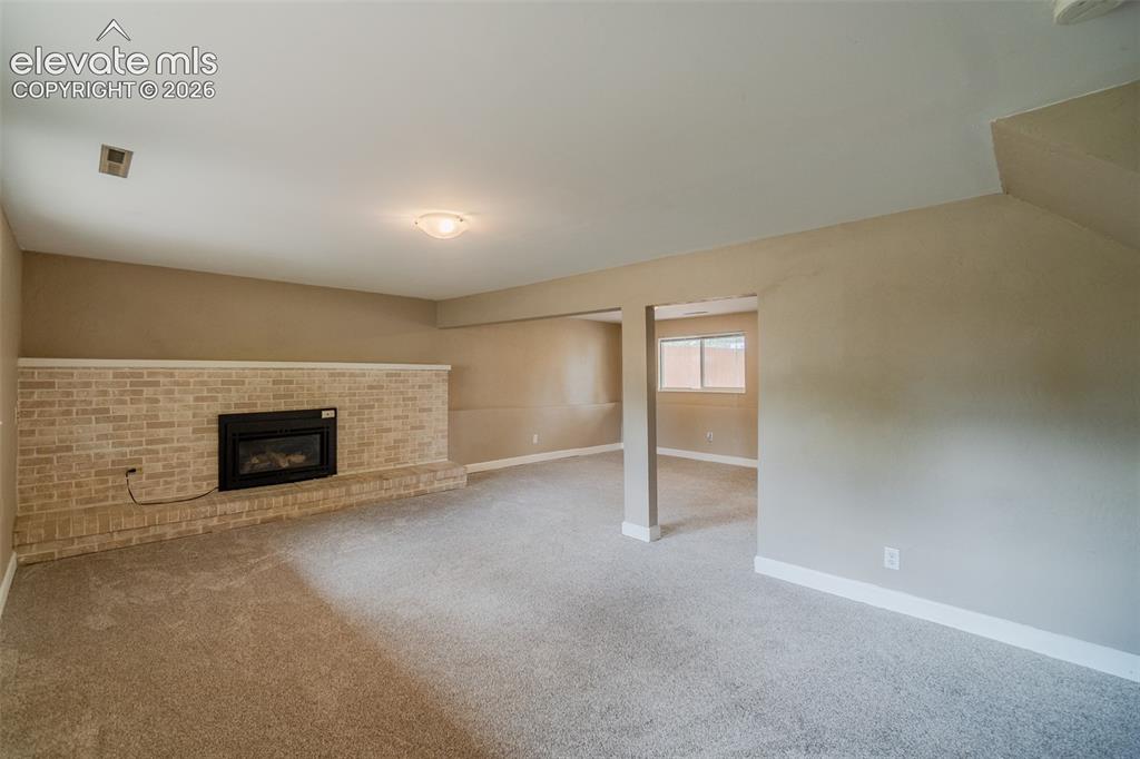 Image 31 of 42: Recessed fireplace with a light brick surround, neutral tone carpeting, and