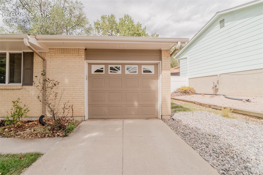Image 34 of 42: Brick exterior with a single-car garage featuring decorative window inserts