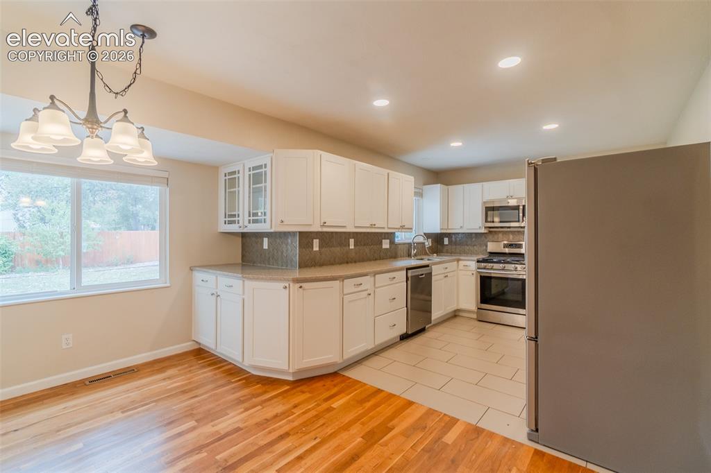 Image 39 of 42: Kitchen featuring white cabinetry with some upper glass fronts, stainless s