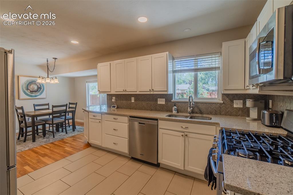 Image 4 of 30: Kitchen with window to the back yard, white shaker cabinetry, stainless ste