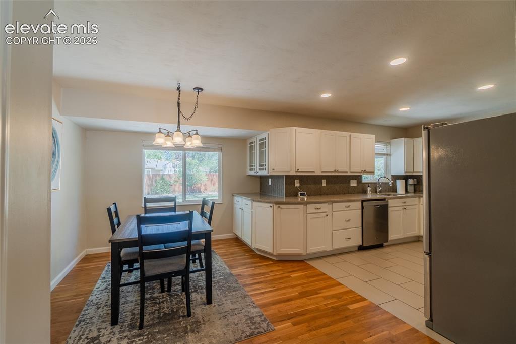 Image 5 of 30: Open-concept kitchen and dining area with white cabinetry, stainless steel