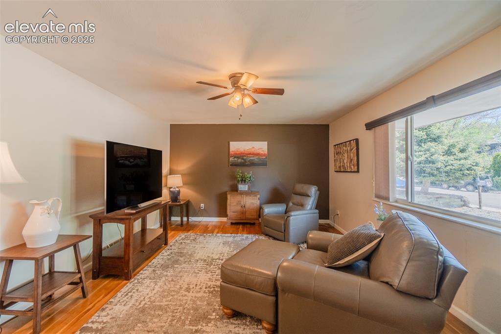 Image 7 of 30: Living area featuring warm wood-finish flooring, a ceiling fan with integra
