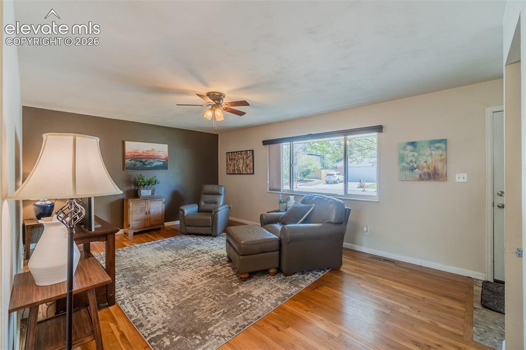 Image 8 of 30: Spacious living area featuring wood-finish flooring, a ceiling fan, and a l