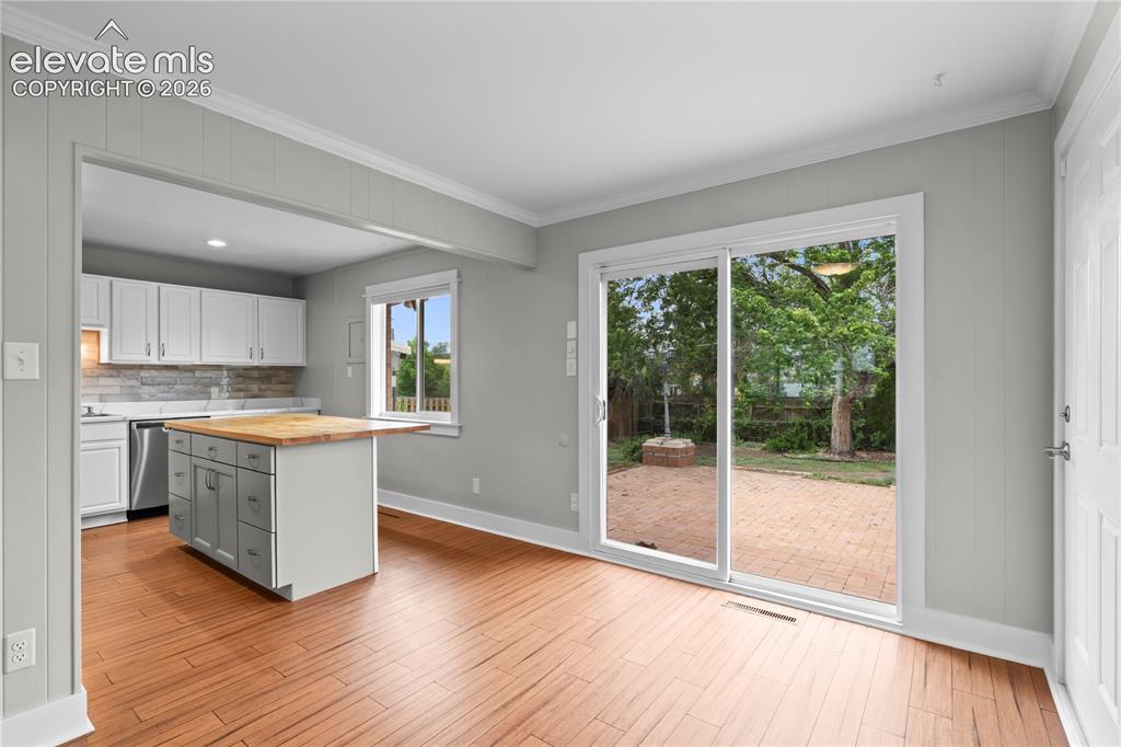 Image 11 of 31: Wood-finish flooring throughout, featuring a kitchen with white cabinetry,