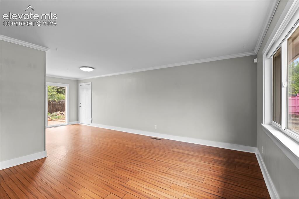 Image 12 of 31: Spacious interior room featuring wood-finish flooring, light gray walls, wh