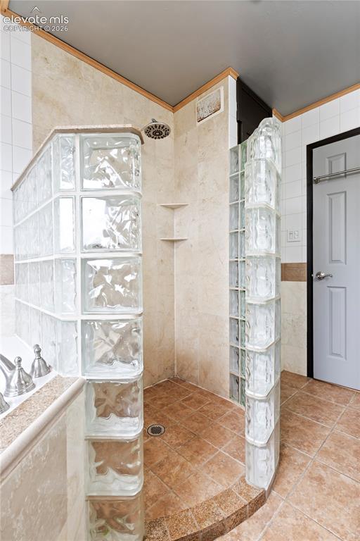 Image 22 of 31: Glass block shower with a tile base and integrated shelving