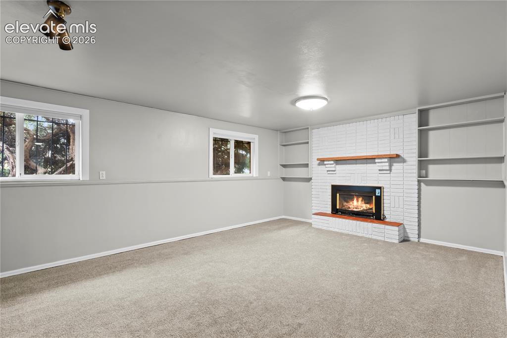 Image 26 of 31: Bonus room featuring built in book shelves and fireplace