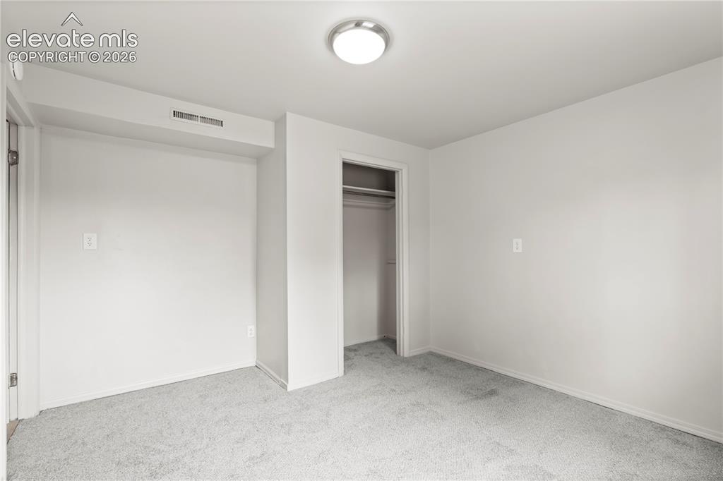 Image 29 of 31: Carpeted room featuring a ceiling-mounted light fixture, recessed wall vent