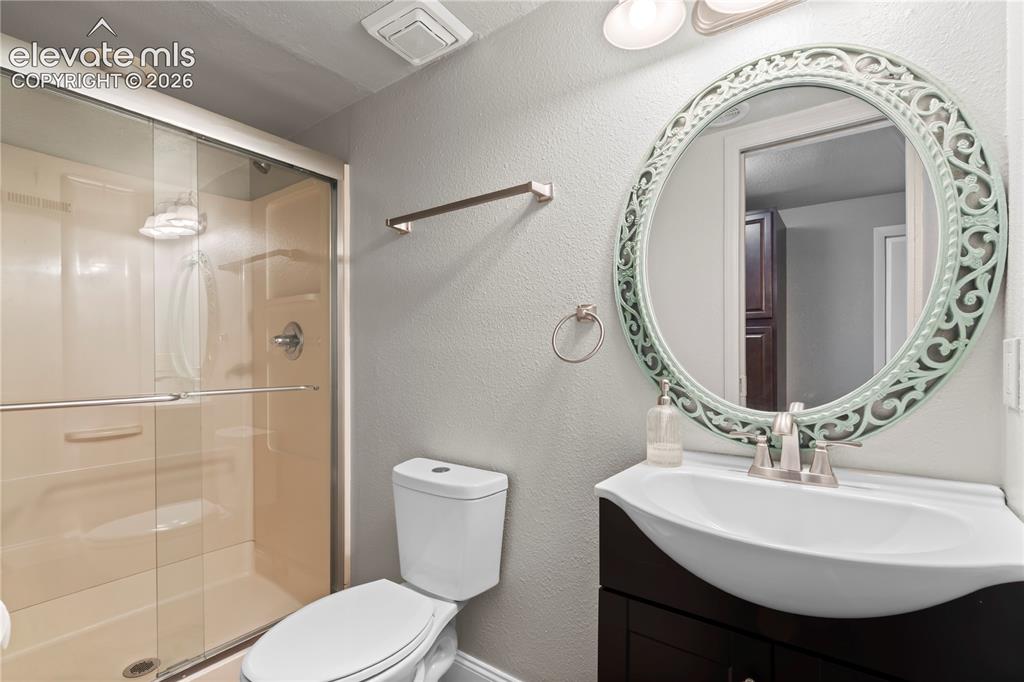 Image 30 of 31: Bathroom featuring a glass-enclosed shower, a dark wood-finish vanity with