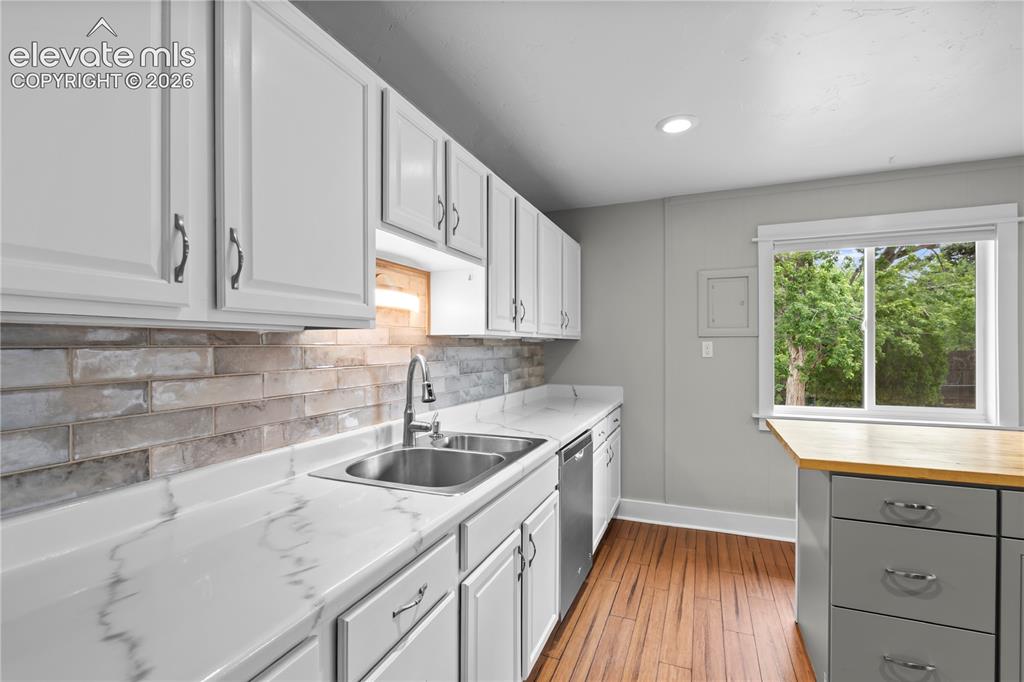 Image 8 of 31: Modern kitchen featuring white cabinetry, a dual-basin stainless steel sink